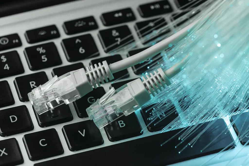 help understand Internet lingo about fiber optics with an image of two ethernet cables, over a keyboard, with fiber optic cables over top of the keyboards.