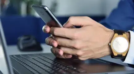 close up of man texting on phone utilizing healthy internet habits and high speed internet upload speed.