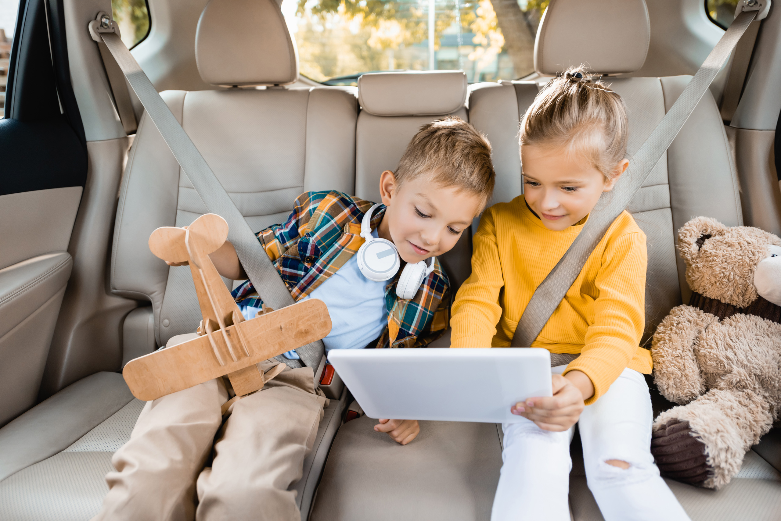 kids watching TV on a mobile device, riding in a car