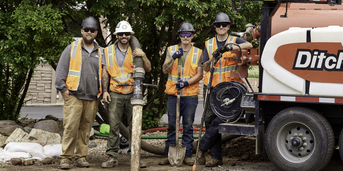 four construction workers posing with equipment