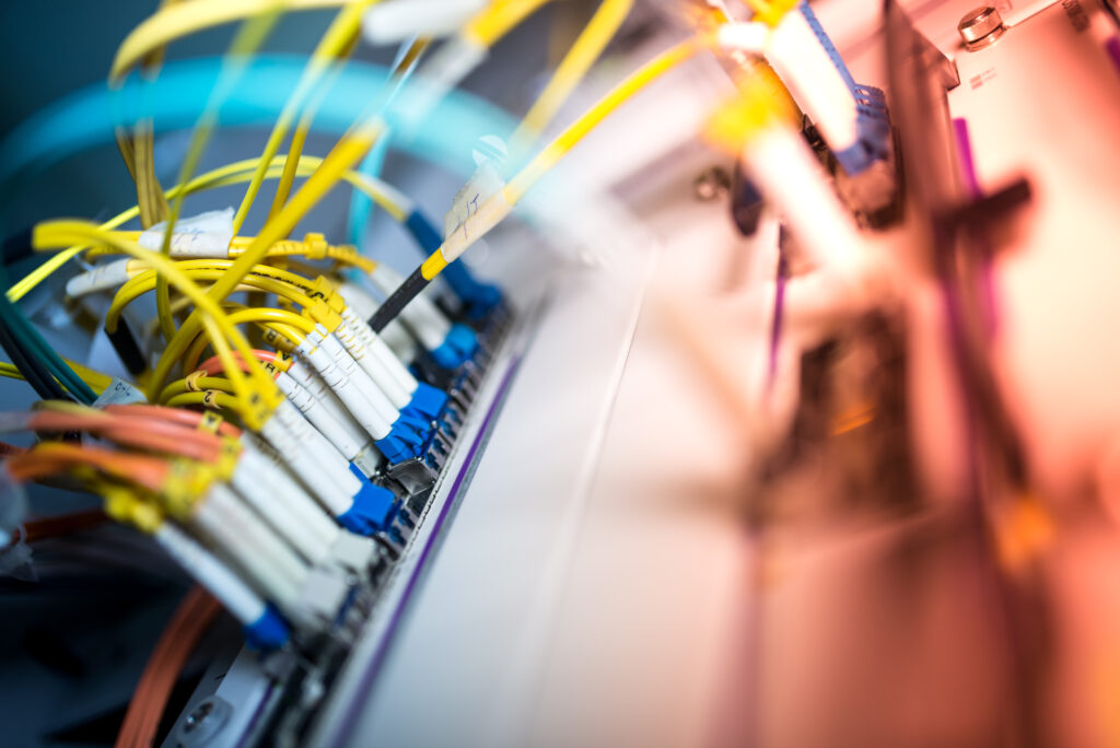 A close-up of fibre optic cables in a network switch. The brightly colored cables emphasize the complex technology that powers home fibre optic internet connections for high-speed data transmission.