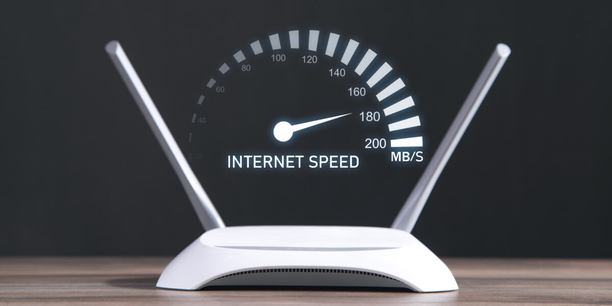 A modern WiFi router with a digital speedometer displaying internet speed, illustrating the question: how much internet speed do I need for optimal performance?