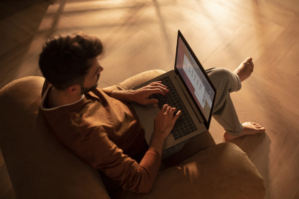 A man working comfortably from home on a laptop, seated on a cushioned chair, demonstrating how a 1000 Mbps internet speed can support smooth, uninterrupted remote work.