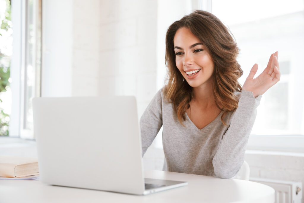 A cheerful woman sitting in a bright classroom environment, using her laptop for online activities, emphasizing the importance of reliable internet speed tests. Keywords: test my internet speed.