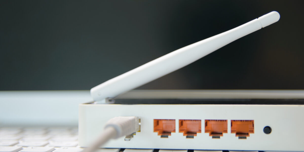 A router with visible Ethernet ports and an antenna, showcasing the concept of "What Does MBPS Mean for Internet?" and the role of router hardware in determining internet speed across devices.