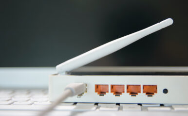 A router with visible Ethernet ports and an antenna, showcasing the concept of "What Does MBPS Mean for Internet?" and the role of router hardware in determining internet speed across devices.