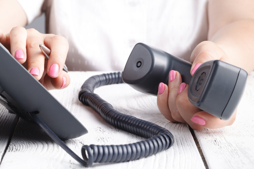 A close-up of a woman's hand holding a phone receiver and dialing a number, highlighting the clarity and dependability of the best landline phone service for both personal and business calls.