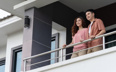 A happy couple stands together on their apartment balcony, enjoying their view. This moment reflects the peace of mind provided by the best internet for apartment, ensuring stress-free connectivity for everyday life.