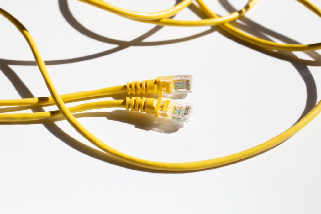  Two bright yellow Ethernet cables with RJ45 connectors lie on a white background, symbolizing reliable connections for achieving the best internet speedtest results.