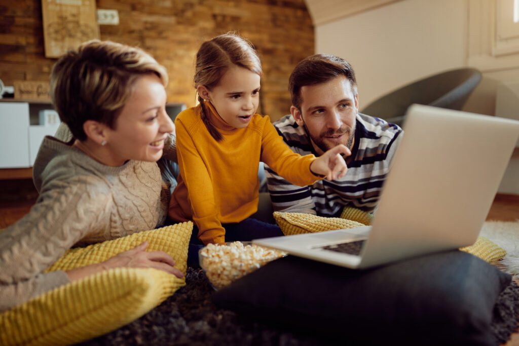 A family of three relaxes at home, watching a laptop together. This image highlights how the best cable internet deals can bring families together for streaming, browsing, and entertainment.