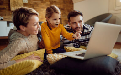 A family of three relaxes at home, watching a laptop together. This image highlights how the best cable internet deals can bring families together for streaming, browsing, and entertainment.