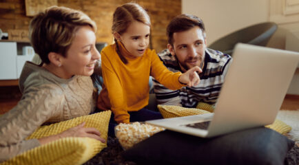 A family of three relaxes at home, watching a laptop together. This image highlights how the best cable internet deals can bring families together for streaming, browsing, and entertainment.