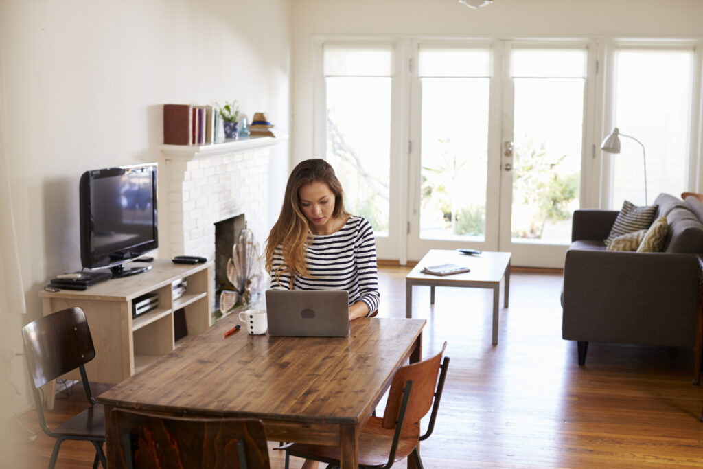 A woman works remotely from her dining table in a bright apartment, showing how the best internet for apartment living supports productive work-from-home environments with reliable connectivity.