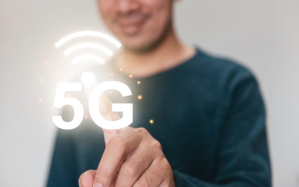 A person interacting with a glowing 5G icon, representing the ability to connect to high-speed internet through advanced wireless technology.