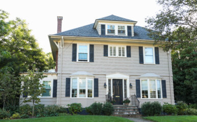 A suburban two-story house with a landscaped yard, illustrating the challenges of achieving reliable WiFi coverage throughout the home. Keywords: "best place to put wifi router in a 2 story house."